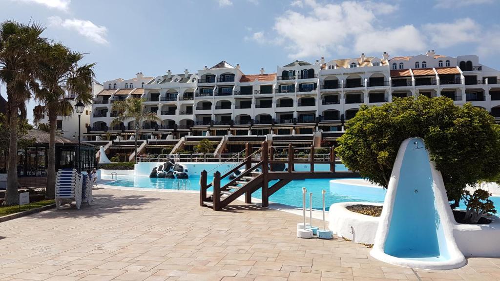 a large hotel with a surfboard in front of a pool at Rocas del Mar Tenerife in Costa Del Silencio