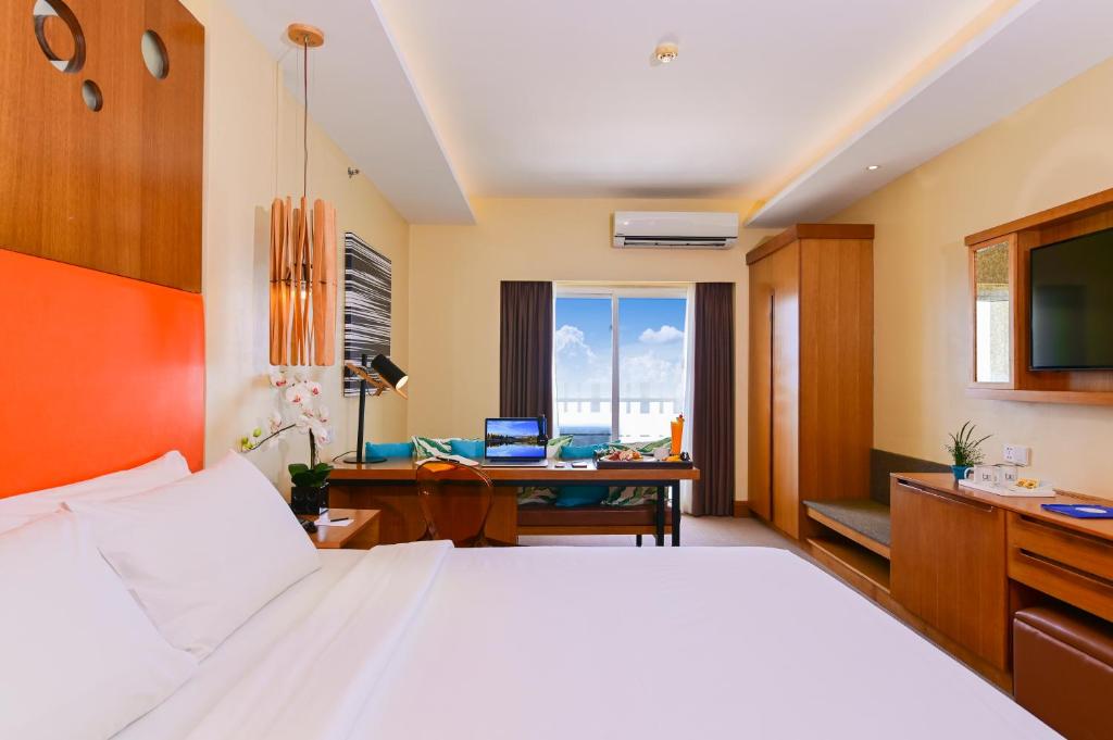a bedroom with a bed and a desk with a laptop at BE Resort Mactan in Mactan