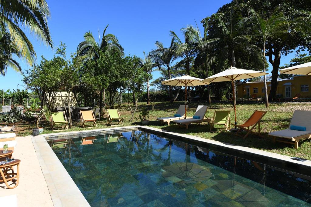 a swimming pool with chairs and umbrellas at Kaz'alala Hosted B&B in Bel Ombre