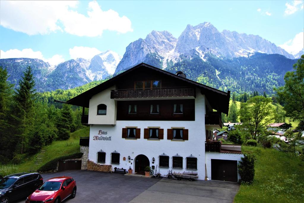 ein großes weißes Gebäude mit Bergen im Hintergrund in der Unterkunft Ferienhaus Waldwinkl in Grainau