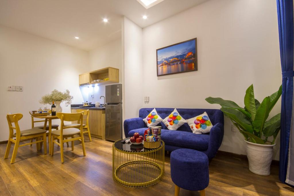 An open-plan suite-style living area with a blue sofa, dining table and kitchenette.