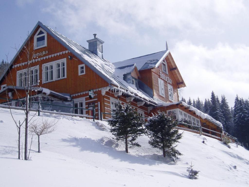 a large wooden house on top of a snow covered slope at Chata Šohajka in Pec pod Sněžkou