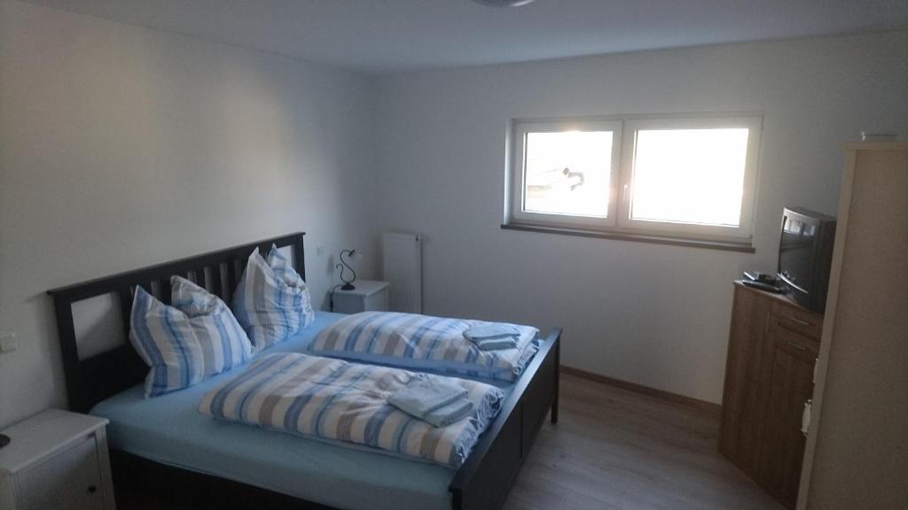 Schlafzimmer mit einem Bett mit blauer Bettwäsche und einem Fenster in der Unterkunft Weingut Edwin Pauly in Palzem