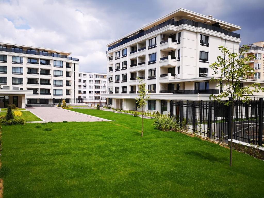 a large white building with a green lawn in front of it at Business and Leisure apartments in Mladost 2 with FREE Garage in Sofia