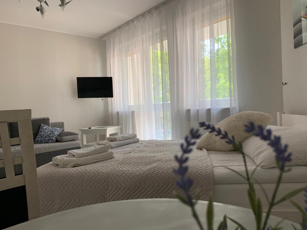 a white bedroom with a bed and a window at Apartament Sloneczny in Kołobrzeg