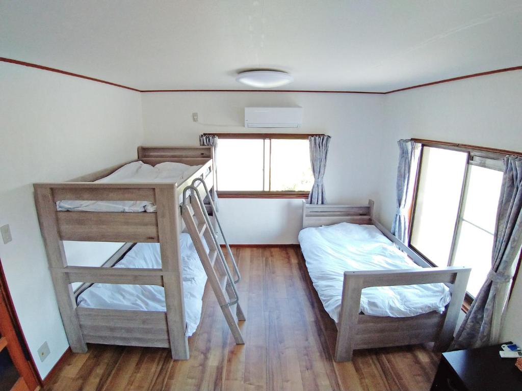 a bedroom with two bunk beds and two windows at ツバメハウス in Tenri