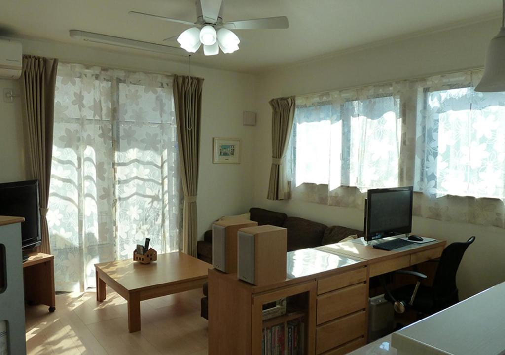 a living room with a couch and a desk with a computer at Kanaloa Funabashi in Funabashi