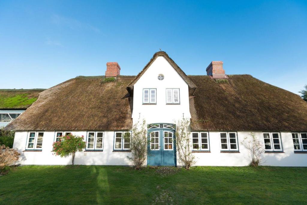 Cette grande maison blanche est dotée d'un toit de chaume. dans l'établissement Hansen-Hof-Wohnung-2, à Tinnum