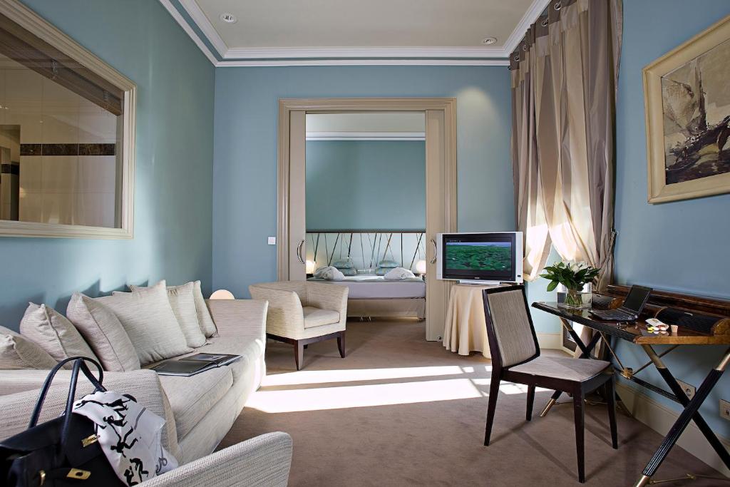 a living room with a couch and a table and a television at Westminster Hotel & Spa Nice in Nice