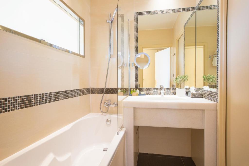 a bathroom with a tub and a sink and a mirror at Westminster Hotel & Spa Nice in Nice