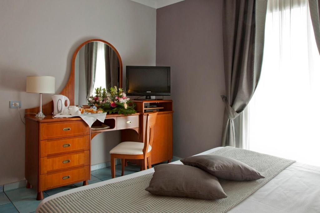 a bedroom with a bed and a desk with a mirror at Hotel Villa Luisa in Pozzuoli