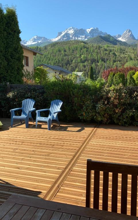 two chairs sitting on a deck with mountains in the background at Chalet Barcelonnette in Barcelonnette