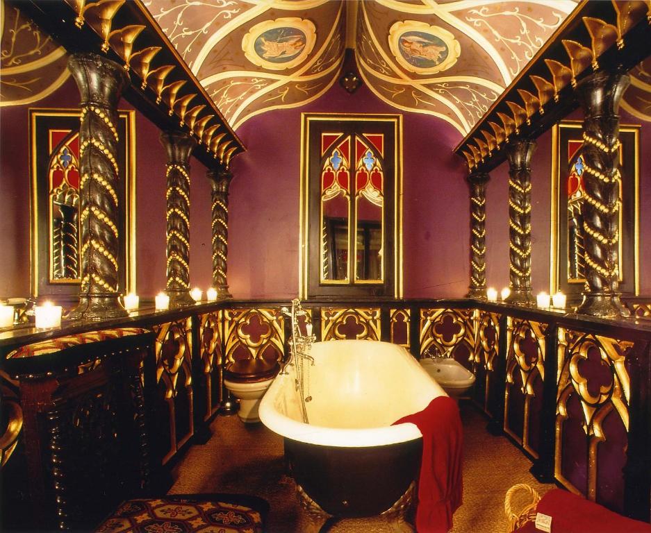 een badkamer met een bad en een paarse muur met kaarsen bij The Witchery by the Castle in Edinburgh