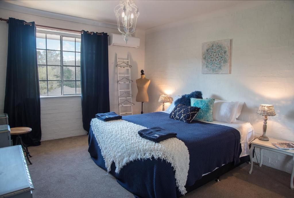 um quarto com uma cama com lençóis azuis e uma janela em Angel Sussurri em Yarramalong