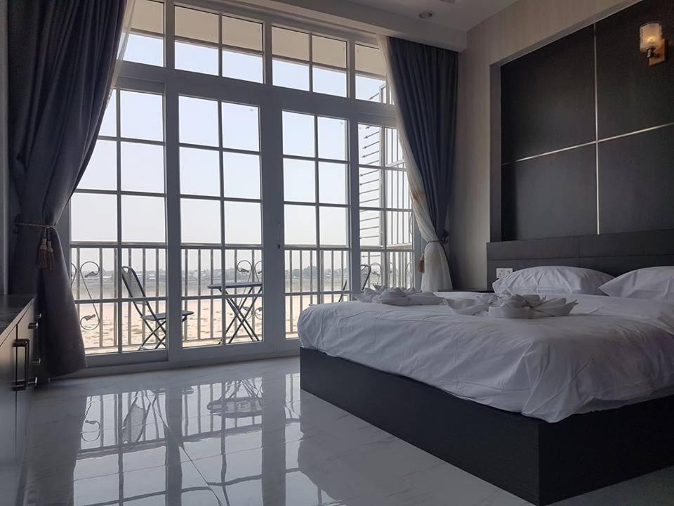 a bedroom with a large bed and a large window at Sunset Mekong Apartment in Vientiane
