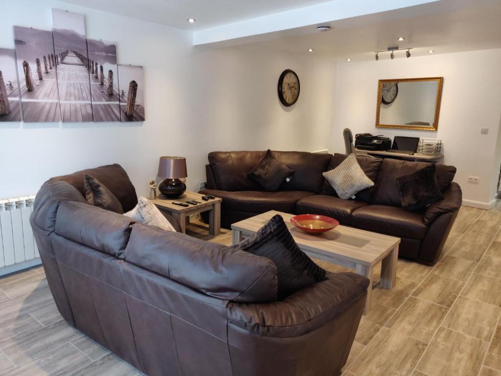 a living room with a leather couch and tables at Dobbies Adults Only Boutique Apartment in Saint-Marcel