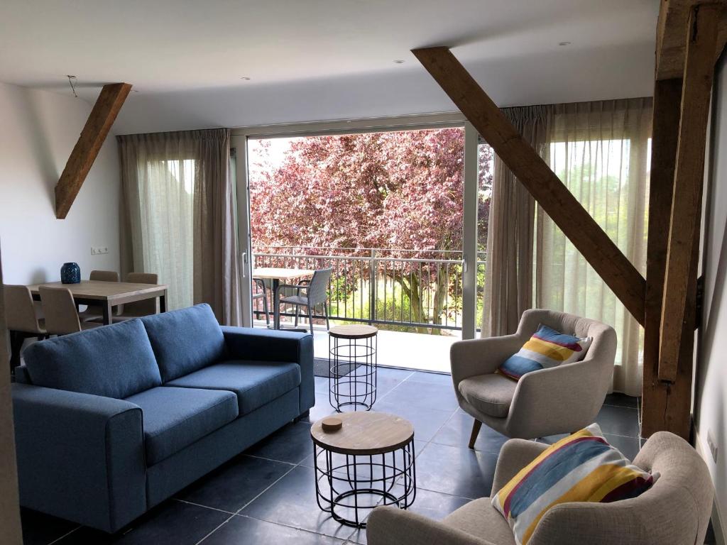 a living room with couches and chairs and a large window at Vakantie Appartementen De Bonte Kraai in Raamsdonk