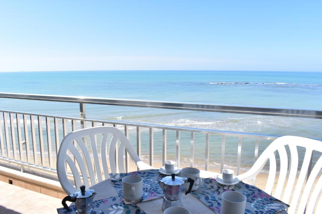 un tavolo e sedie su un balcone con vista sull'oceano di Casa Donna Titina a Punta Secca
