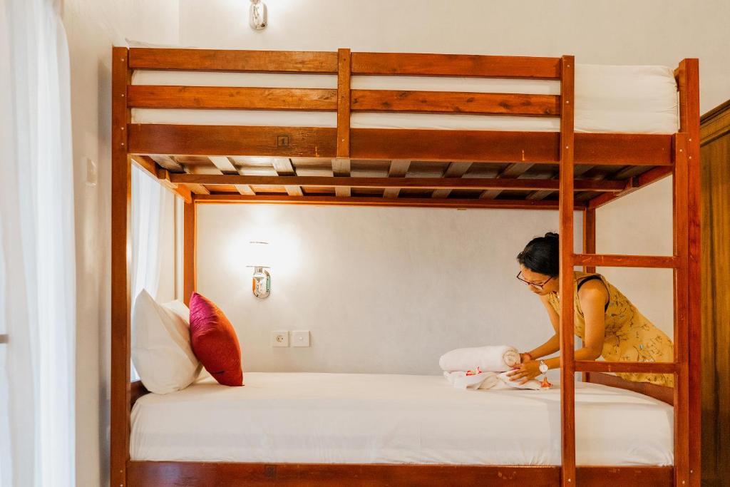 a woman in a yellow dress sitting on a bunk bed at Kamasanti Hostel in Nusa Penida