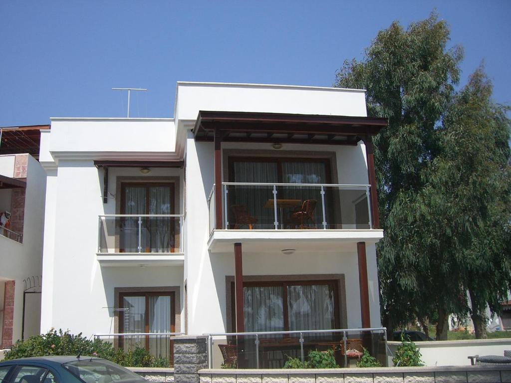 a white building with a balcony and a tree at Oasis Apart in Turgutreis