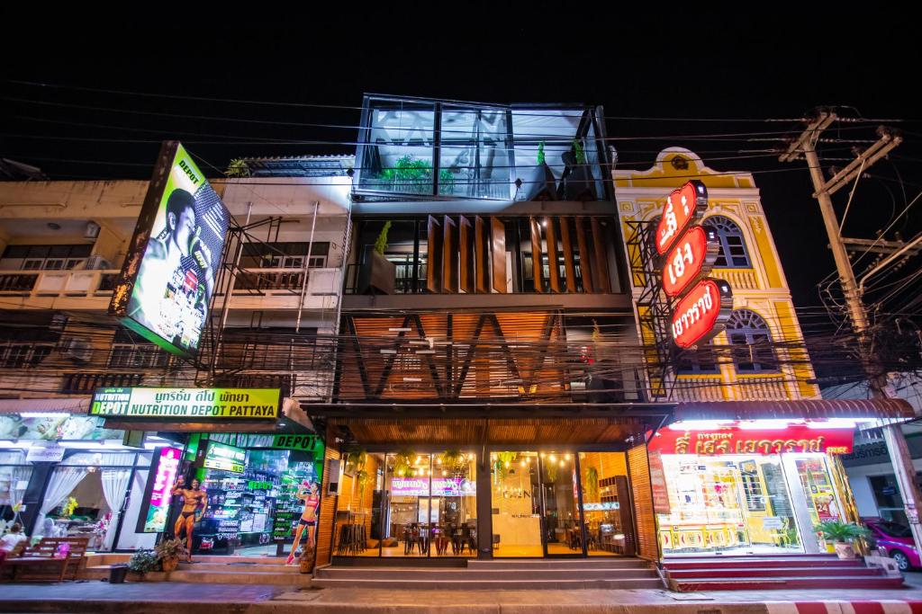 a building with neon signs on the side of it at Kaen Hostel in Pattaya