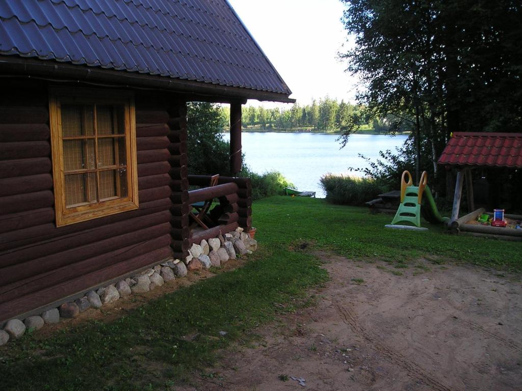 a house with a window and a playground next to the water at Lõõdla Holiday House in Lümatu