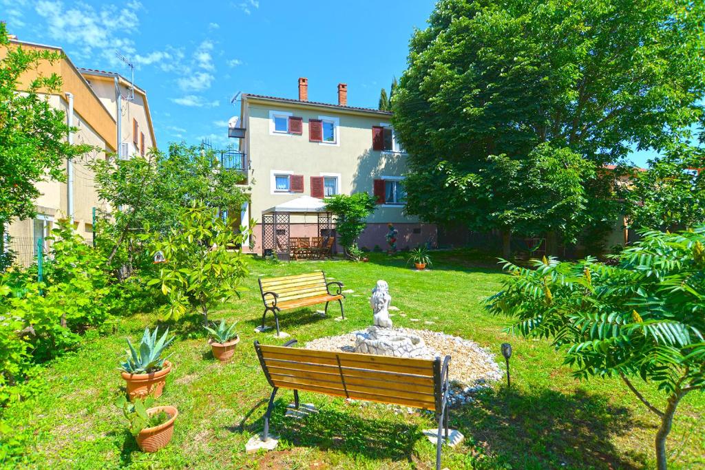 un parc avec un banc et une fontaine en face d'une maison dans l'établissement Apartment Pineta 1817, à Fažana