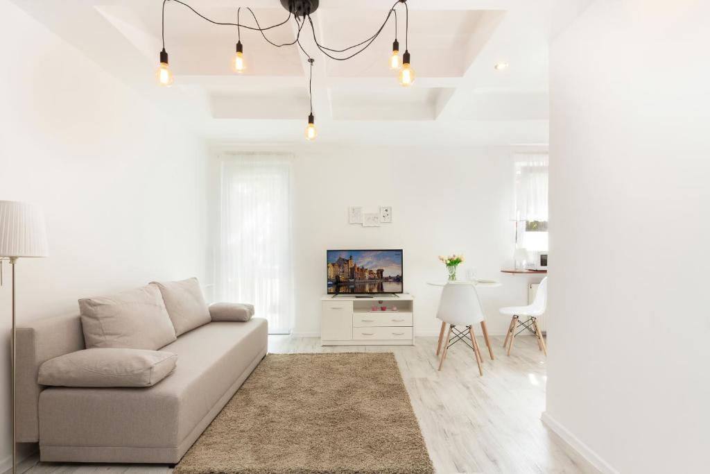 a white living room with a couch and a table at Apartments Gdańsk Dworska by Renters in Gdańsk
