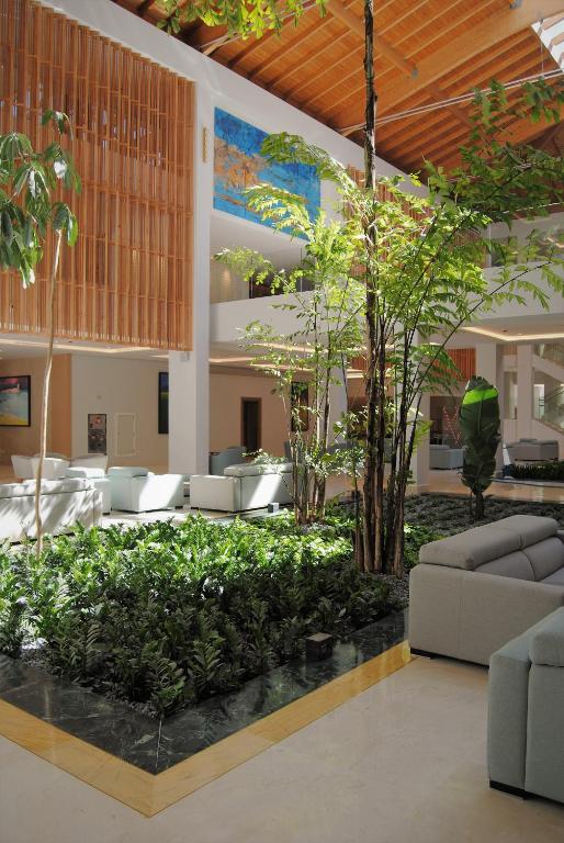 a lobby with couches and trees in a building at Hipotels Barrosa Park in Chiclana de la Frontera