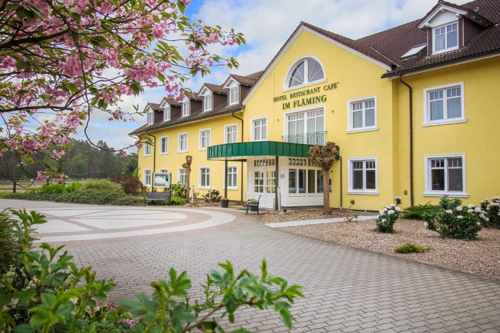 ein gelbes Gebäude mit einem Schild auf der Vorderseite des Gebäudes in der Unterkunft Ferien Hotel Fläming in Niemegk