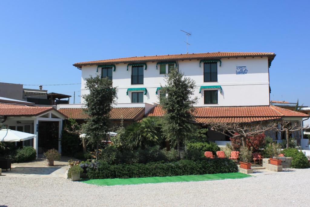 a large white building with trees in front of it at Albergo Ristorante Alla Lanterna in Fano