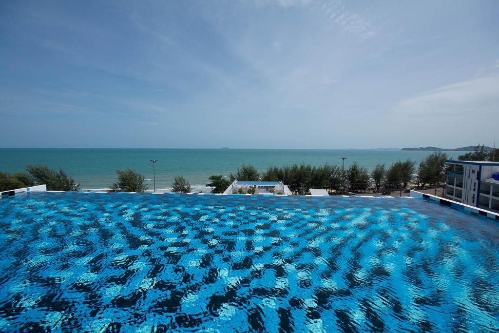 a large blue swimming pool with the ocean in the background at Grandbeach2 B52 By malai in Mae Pim
