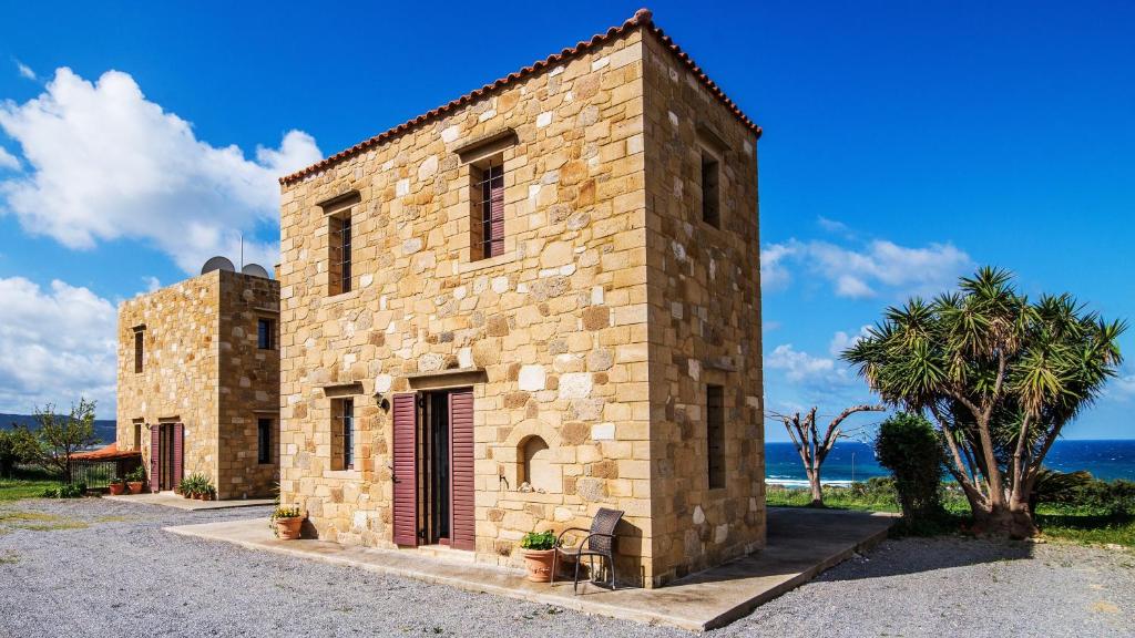 a stone building with a palm tree in front of the ocean at Stay in Falassarna in Falasarna