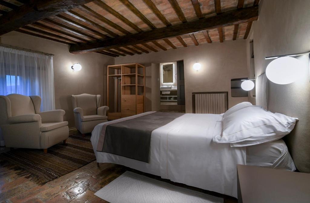 a bedroom with a large white bed and two chairs at Le Silve di Armenzano in Assisi