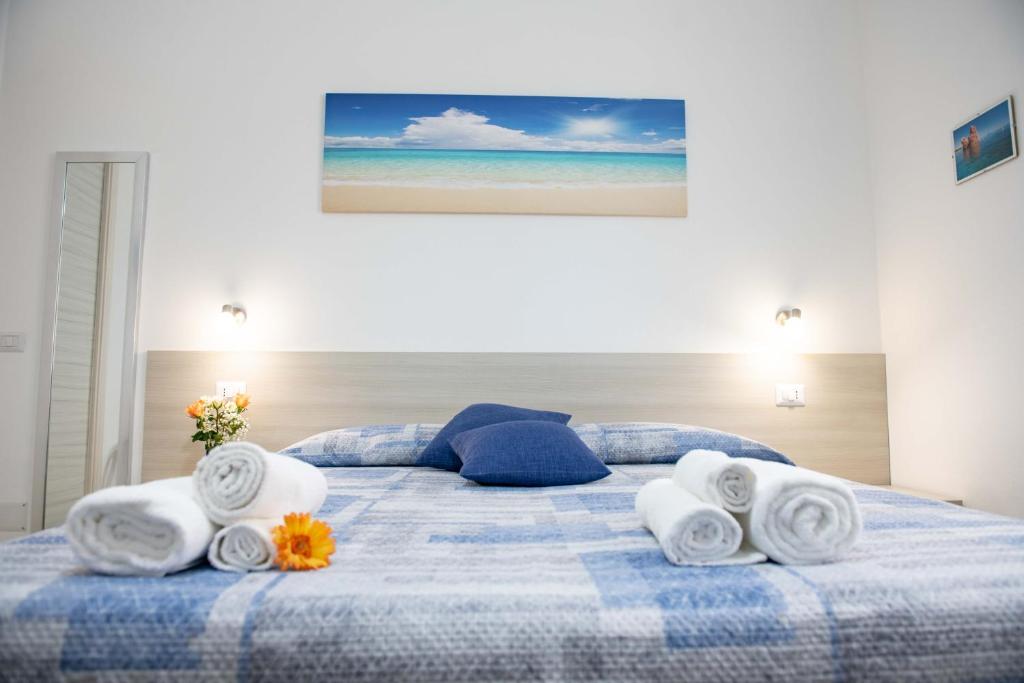 a blue and white bed with towels and flowers on it at B&B Il Viaggiatore in Tortolì