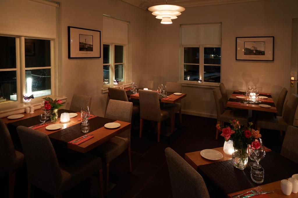 a restaurant with wooden tables and chairs and windows at Fosshotel Eastfjords in Fáskrúðsfjörður