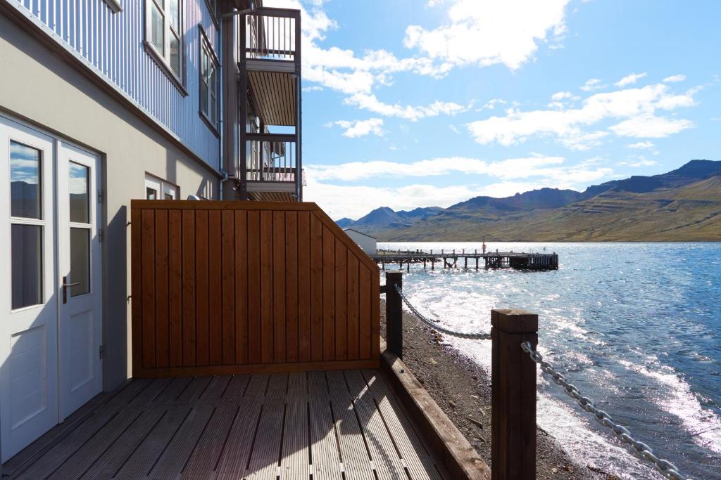 a building with a wooden deck next to the water at Fosshotel Eastfjords in Fáskrúðsfjörður