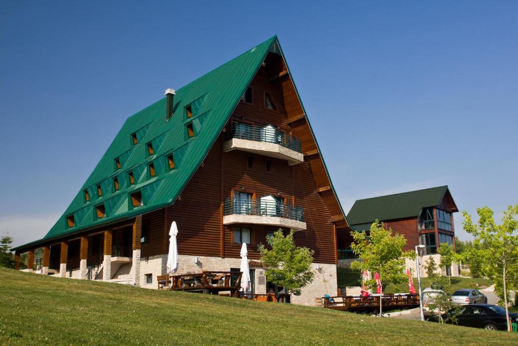 ein Gebäude mit einem grünen Dach auf einem Hügel in der Unterkunft Hotel Polar Star in Žabljak