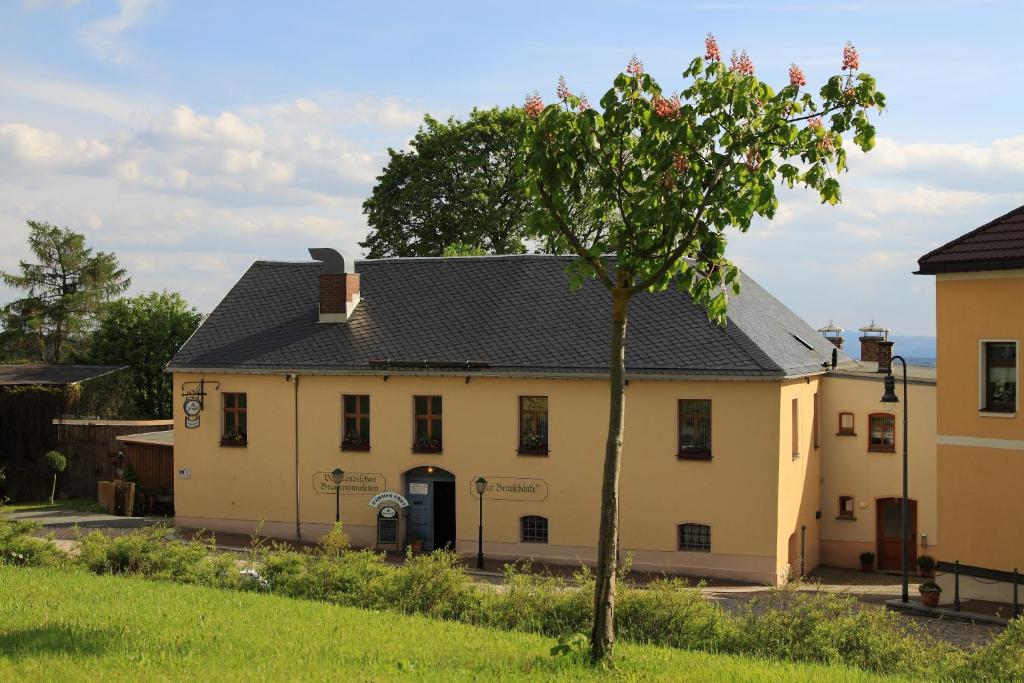 Una casa blanca con un árbol delante. en Pension und Gaststätte "Zur Brauschänke", en Schöneck