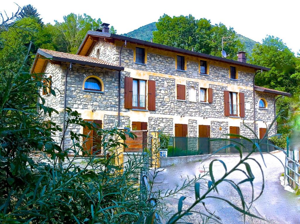 ein großes Steingebäude mit Bäumen davor in der Unterkunft Agriturismo Il Talento Nella Quiete in Castiglione dʼIntelvi