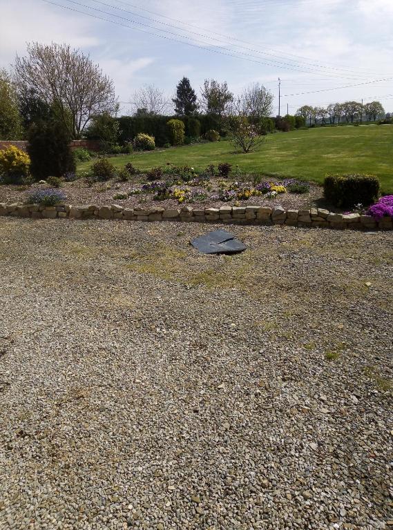 un jardín con una cama de flores y una pared de piedra en les conillieres en Congrier