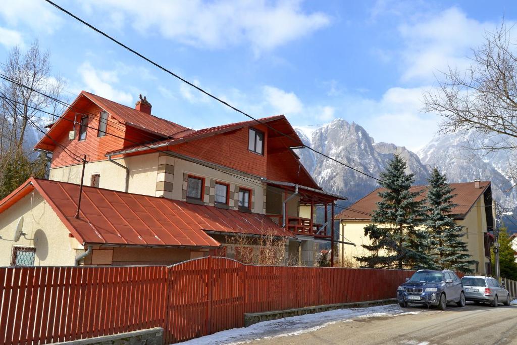 uma casa com um telhado vermelho em frente a uma montanha em VILA MARIS BUSTENI em Buşteni