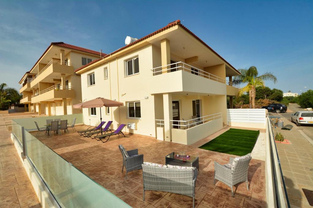 a view of a house with chairs and a patio at Nissi Martha Apartment in Ayia Napa