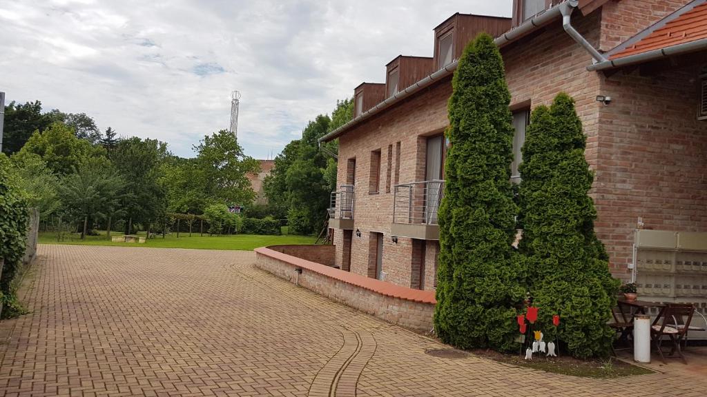 ein paar Bäume neben einem Backsteingebäude in der Unterkunft Gyulai Fürdö Apartman in Gyula