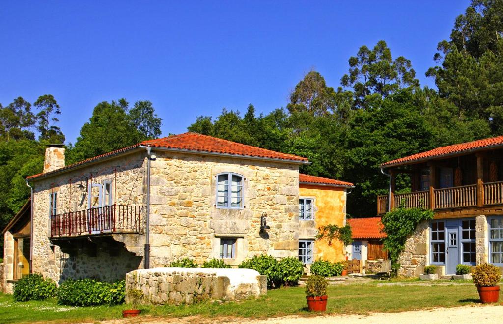 ein altes Steinhaus mit einer Veranda und einem Balkon in der Unterkunft Casa do Castelo de Andrade in Puentedeume