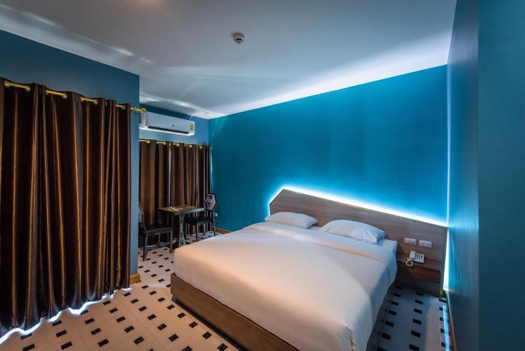 a blue bedroom with a bed and a blue wall at The Feeling Hotel in Rayong