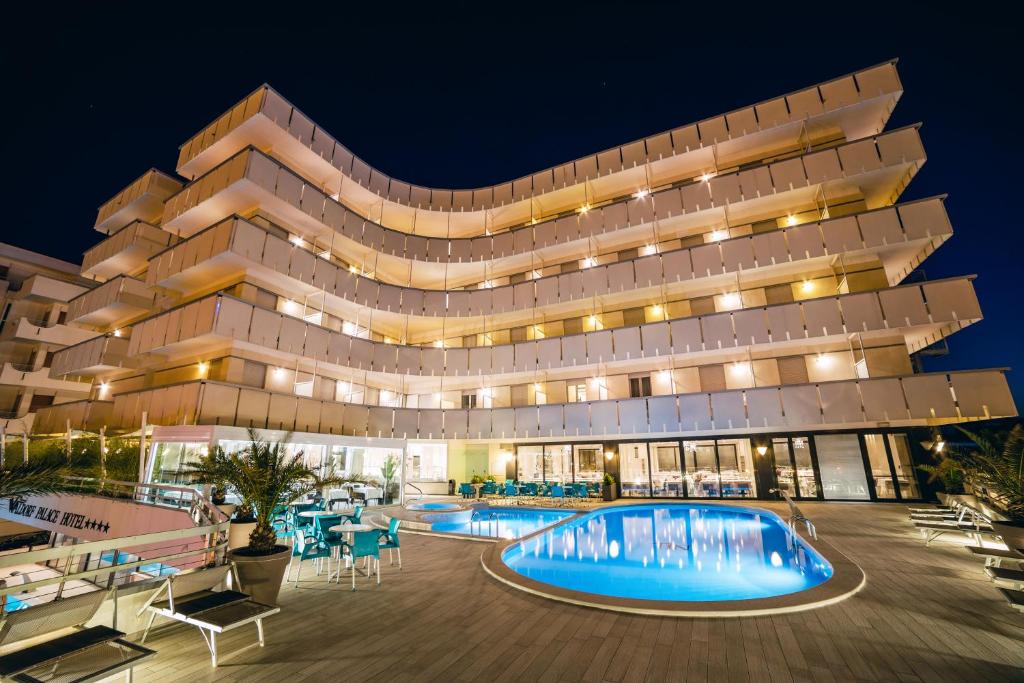 a building with a swimming pool at night at Waldorf Palace Hotel in Cattolica