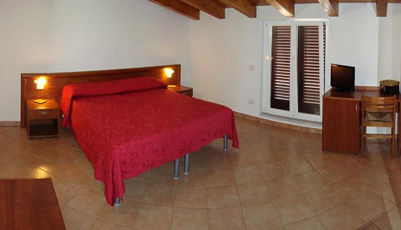 a bedroom with a red bed and a television at Albergo Antica Luni in Luni
