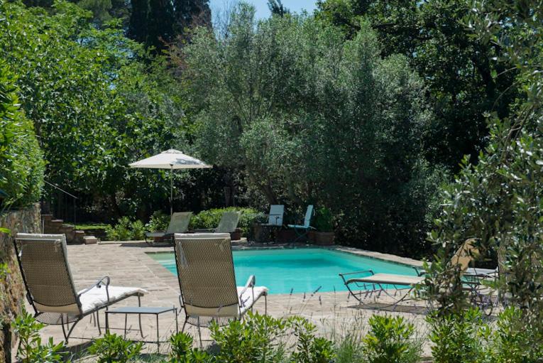 a swimming pool with two chairs and an umbrella at L' Insolita in Venturina Terme