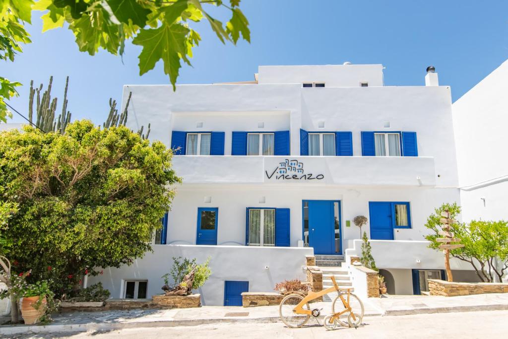 un edificio blanco con puertas azules y una bicicleta delante en Vincenzo Family Rooms, en Tinos